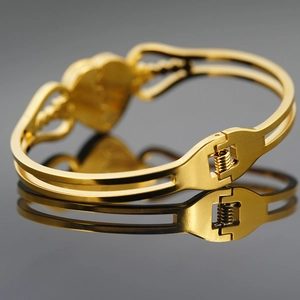 Golden stainless steel heart bracelet with dual-line hollow design on a mirror surface