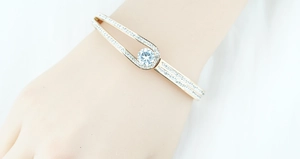 Detail of rose gold bangle with pave crystals and center stone on model wrist