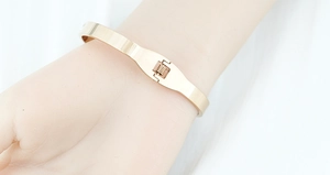 Macro view showing the spring hinge mechanism of a rose gold polished steel bangle