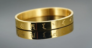 Makroaufnahme eines goldenen Titanstahl-Armbands mit eingravierten buddhistischen Symbolen