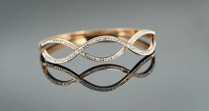 Close-up of rose gold twisted bangle with sparkling pavé crystals and mirrored reflection