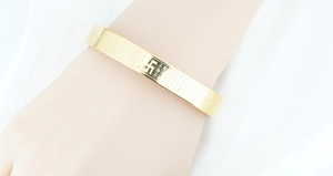 Detailansicht eines goldenen Titanstahl-Armreifens mit gravierten buddhistischen Schriften