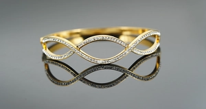 Close-up of gold plated intertwined wave bracelet with shimmering cubic zirconia stones