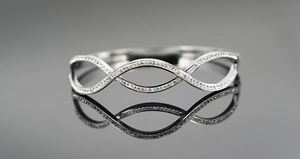 Detailed macro shot of silver wave bangle with sparkling pave-set cubic zirconia stones