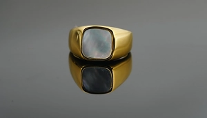 Vista macro de anillo de acero de titanio dorado pulido con nácar gris oscuro incrustado