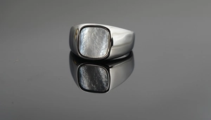 Detalle macro de un anillo de acero plateado con incrustación de nácar cuadrado