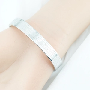 Polished silver titanium steel bangle featuring intricate engraved Buddhist scriptures
