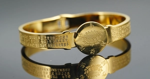Macro detail of gold Buddhist Heart Sutra engraving and lotus relief on a flat metal bangle