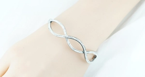 Close-up of silver-tone wave bangle featuring micro-pave white cubic zirconia stones