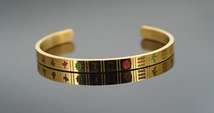 Detail view of gold titanium steel bangle with engraved colorful Mahjong tile patterns