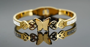 Vista macro di un bracciale a farfalla dorato con finitura satinata e strass trasparenti