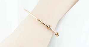 Dettaglio del bracciale minimalista in oro rosa con due anelli mobili e zirconi incastonati