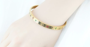Detail of gold-plated mahjong bangle featuring traditional Chinese characters on wrist