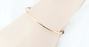 Bracciale rigido minimalista in acciaio al titanio dorato indossato al polso