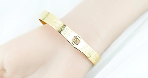 Macro detail of gold-plated stainless steel cuff bracelet with engraved Buddhist scriptures