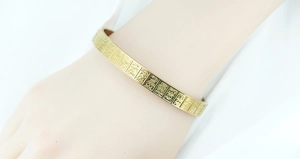 Macro detail of gold plated titanium steel bracelet with engraved classical inscriptions