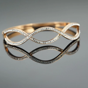 Elegant rose gold wave bracelet with sparkling zircons on a reflective grey surface