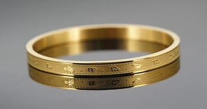 Macro shot of gold-plated stainless steel bangle with engraved ancient symbols
