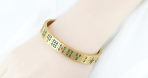 Detail of gold-plated mahjong bangle featuring engraved characters with colorful enamel fill