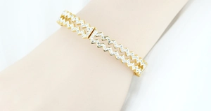 Detail shot of golden titanium steel bangle featuring dual zigzag rows and inlaid crystals