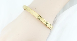 Detailed macro view of gold stainless steel open bangle with ancient Sanskrit patterns