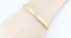 Detailed macro view of the gold-plated titanium steel bracelet with engraved Sanskrit text