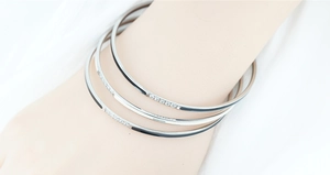 Close-up of three-piece silver titanium steel bangles with diamonds and black enamel inlay