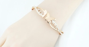 Detailopname van een roségouden vlinderarmband met sprankelende kristallen op pols
