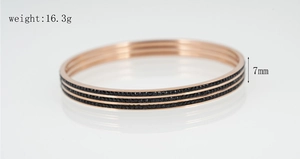 Vue détaillée du jonc en titane or rose 7mm orné de trois rangées de zircons noirs brillants