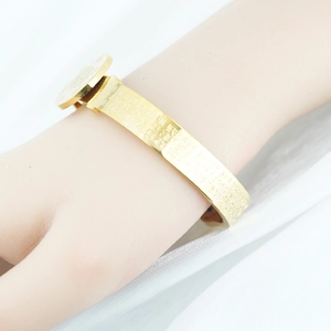 Golden flat wide open cuff bangle with engraved Buddhist scriptures and round charm