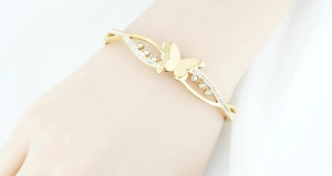 Detailopname van de gouden vlinderarmband met sprankelende kristallen om de pols