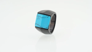 Détail d'une bague en titane noir mat avec une incrustation de turquoise carrée veinée