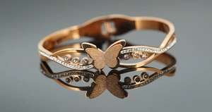 Detail van een roségouden vlinderarmband met micro-pave kristallen en matte afwerking