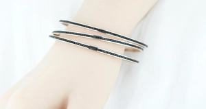 Détail de trois bracelets joncs en or rose avec cristaux de zircon noirs sertis pavé