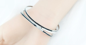 Detailed view of silver stacking bracelets with black and white enamel and diamonds