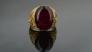 Detailed side view of a vintage gold steel ring featuring intricate filigree and a red ruby