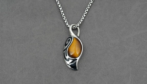 Macro detail of retro tiger eye stone pendant with tribal engraving and box chain
