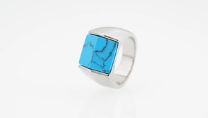 Détail macro d'une bague en acier titane argenté avec incrustation de turquoise carrée