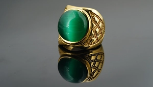 Détail macro d'une bague chevalière dorée pour homme avec pierre œil de chat verte