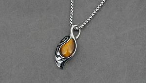 Macro detail of teardrop tiger eye stone with tribal engraved silver pendant and box chain