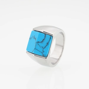 Bague en acier titane poli avec pierre de turquoise carrée sur fond blanc éclatant