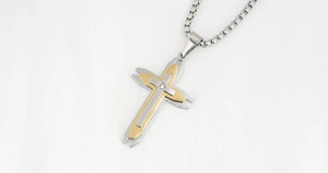 Détail du pendentif croix bicolore or et argent avec un petit zircon serti au centre