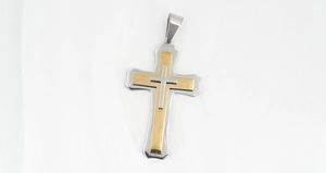 Detailed close-up of a three-layer stainless steel cross pendant in gold and silver