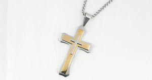 Macro detail of layered silver and gold cross pendant with a stainless steel box chain