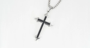 Macro shot of a gothic silver cross pendant with black inlay and stainless steel box chain