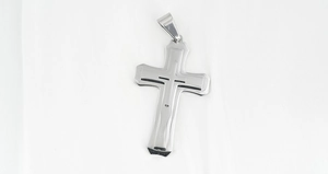 Macro detail of the triple-layered stainless steel cross pendant with a polished silver finish