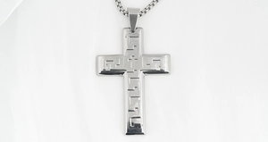 Close-up of titanium steel cross pendant with meander pattern on a box chain