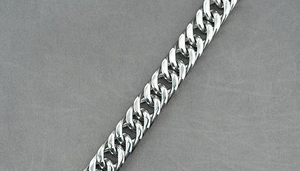 Macro close-up of a silver polished stainless steel curb link chain with mirror finish