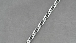 Macro shot of polished silver Cuban link chain showing flat-jointed metal structure