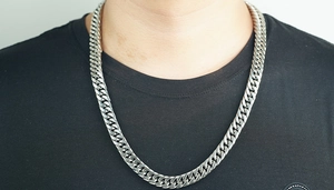 Close-up of a high-polished silver stainless steel Cuban link chain necklace on a model